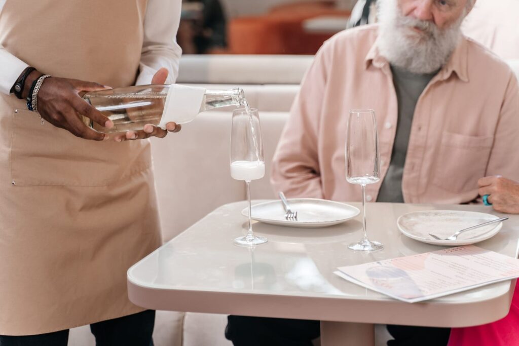 Waiter pouring a drink for a guest seated at a restaurant table