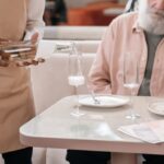 Waiter pouring a drink for a guest seated at a restaurant table